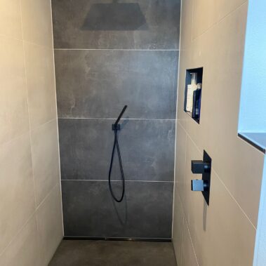 Moderne Walk-in-Dusche mit großformatigen Fliesen, Regendusche und integrierter Ablagenische.