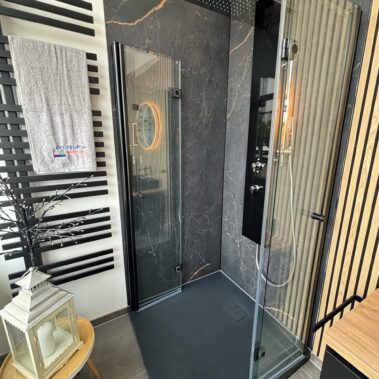 Hochwertige Dusche mit schwarzer Marmoroptik, Glasabtrennung und Regendusche.