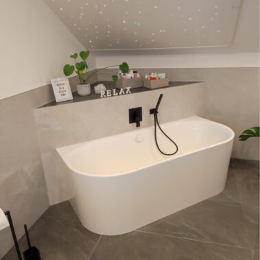 Modernes Badezimmer mit freistehender Badewanne, Sternenhimmel-Decke und schwarzen Armaturen.